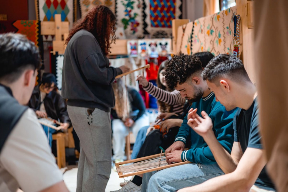 Participants concentrating on their looms